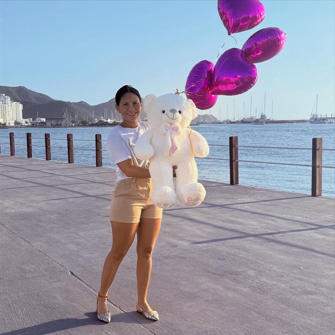 Cliente de Enkntadas con un peluche gigante y globos de corazón en el malecón de Santa Marta