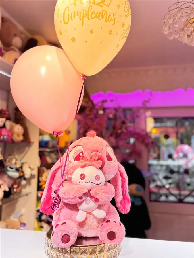 Peluche rosado abrazando otro peluche, con globos en tonos pastel