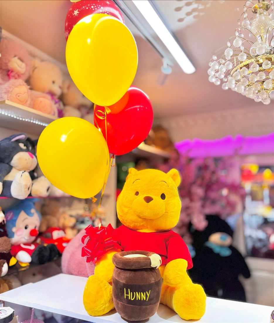 Peluche de Winnie the Pooh con tarro de miel y globos amarillos y rojos